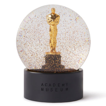 An Oscar statuette snow globe with gold glitter, housed in a special Academy Awards box gift box.
